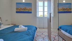 Ein Schlafzimmer mit einem Bett, einer Tür und zwei Bildern an der Wand.