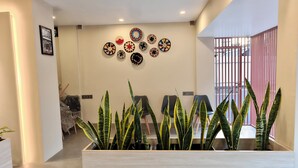 A modern interior with a reception desk, potted plants, and decorative wall art. - AYWA Hotels (Kanayannur)
