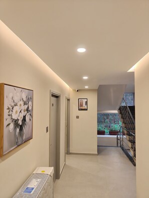 A hallway with a painting of flowers, a door, a framed picture, and a staircase. - AYWA Hotels (Kanayannur)