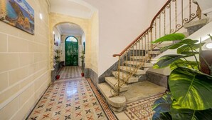 A hallway with patterned flooring, a green door, and a staircase with a wrought iron railing. - Private Room in Hamrun with Shared Kitchen (Hamrun)