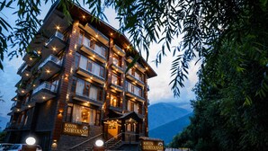 Ein mehrstöckiges Gebäude mit Balkonen, einer Treppe und Hinweisschildern für 'Kavin Suryanash Manali'.