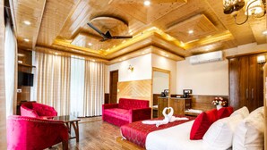 Ein Hotelzimmer mit Holzboden, einem Bett mit rot-weißer Bettwäsche, einem roten Sessel, einem Holztisch und einem Spiegel.