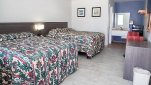 Een hotelkamer met twee bedden, een bureau, een stoel, een televisie en een spiegel.
