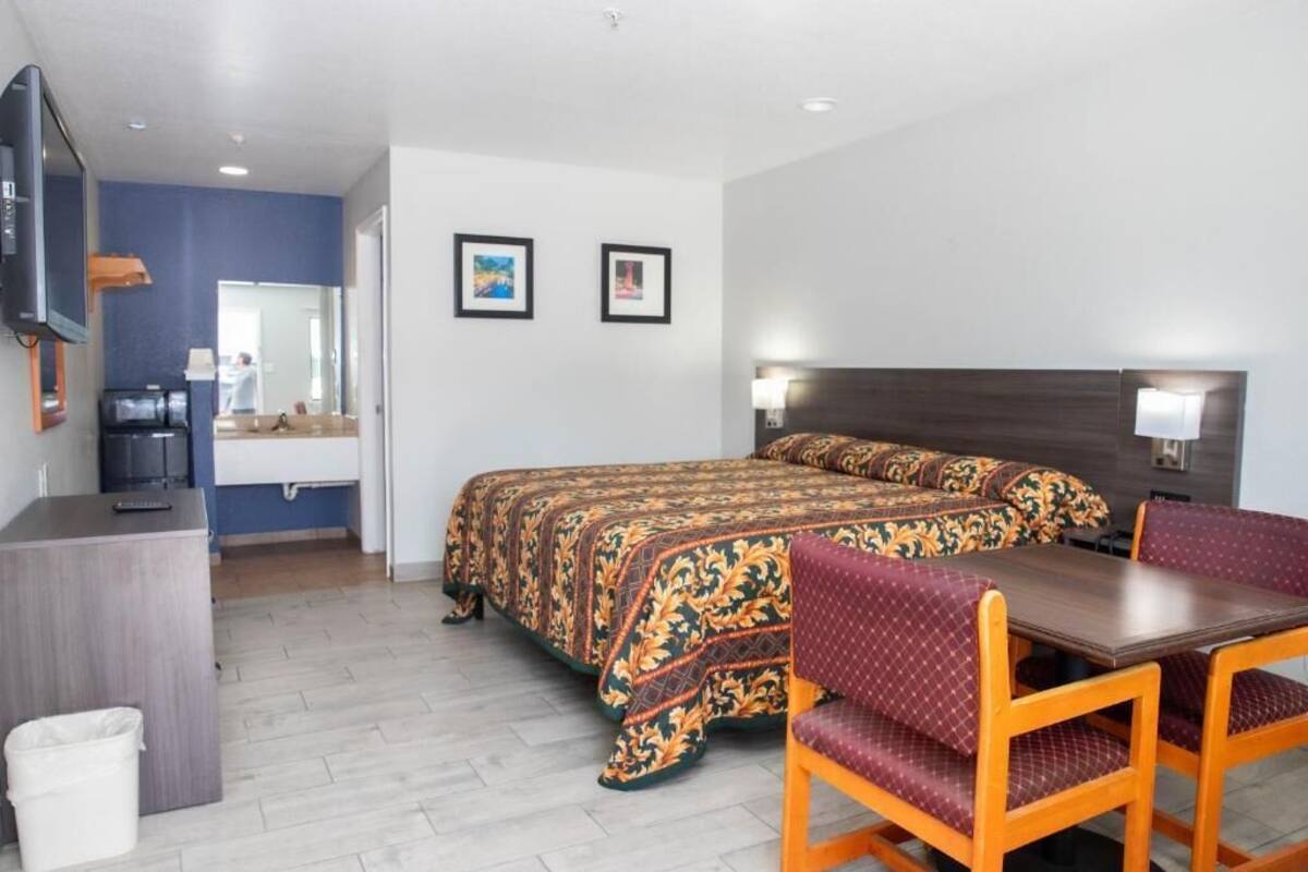 Habitación de hotel con cama, escritorio, silla y televisión.