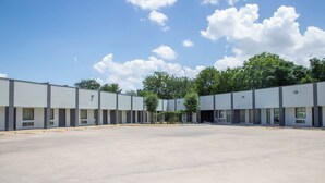 Een ruime, lege parkeerplaats met een rij moderne, laagbouwwoningen.