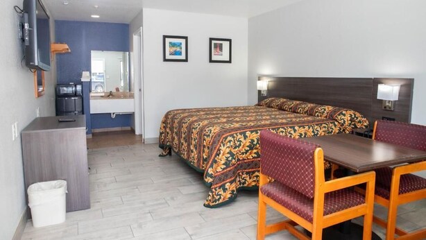 Hotelkamer met een bed, een bureau, een stoel, een televisie en twee ingelijste foto’s aan de muur.