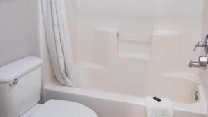 Een badkamer met toilet, bad en douchegordijn.