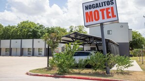 Een motel genaamd Nogalitos met een overdekte parkeerplaats en een gebouw met meerdere ramen.