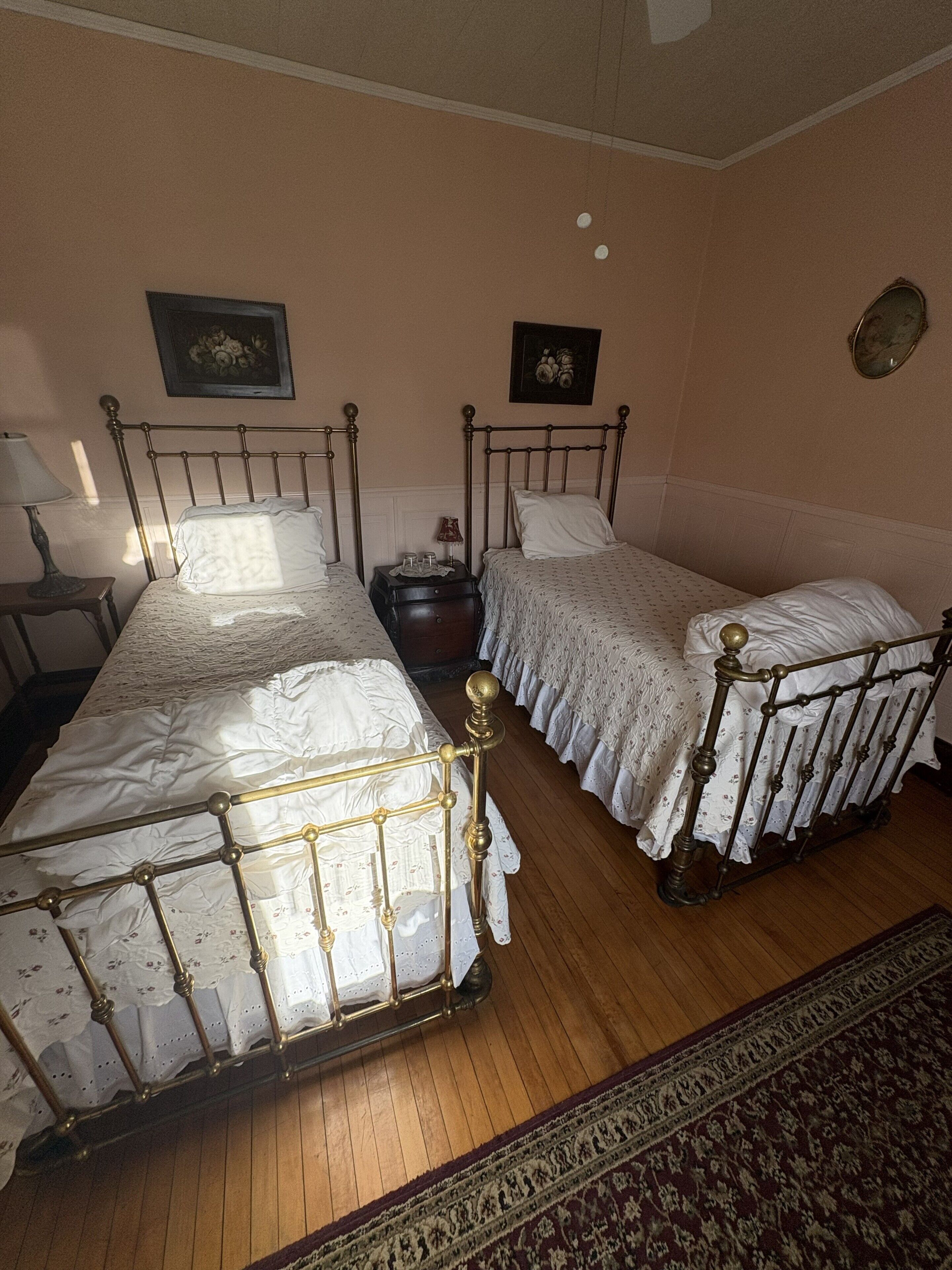 A room with two beds, a nightstand, a lamp, and a rug.
