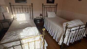 A room with two beds, a nightstand, a lamp, and a rug.