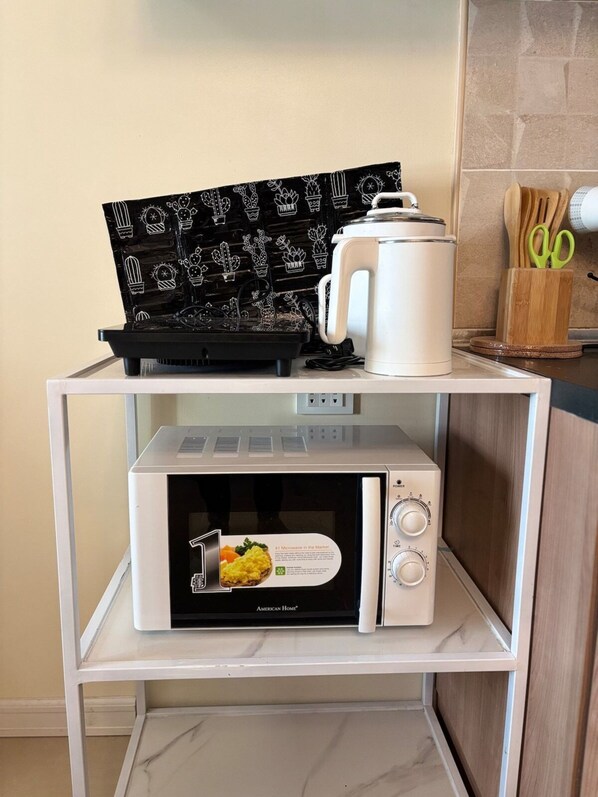 A kitchen with a microwave, a coffee maker, and a tray with a cactus pattern. - Modern Comfort at Avida Towers Riala (Cebu City)