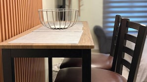 A dining table with a metal bowl, a wooden chair, and a vertical wooden panel. - Modern Comfort at Avida Towers Riala (Cebu City)
