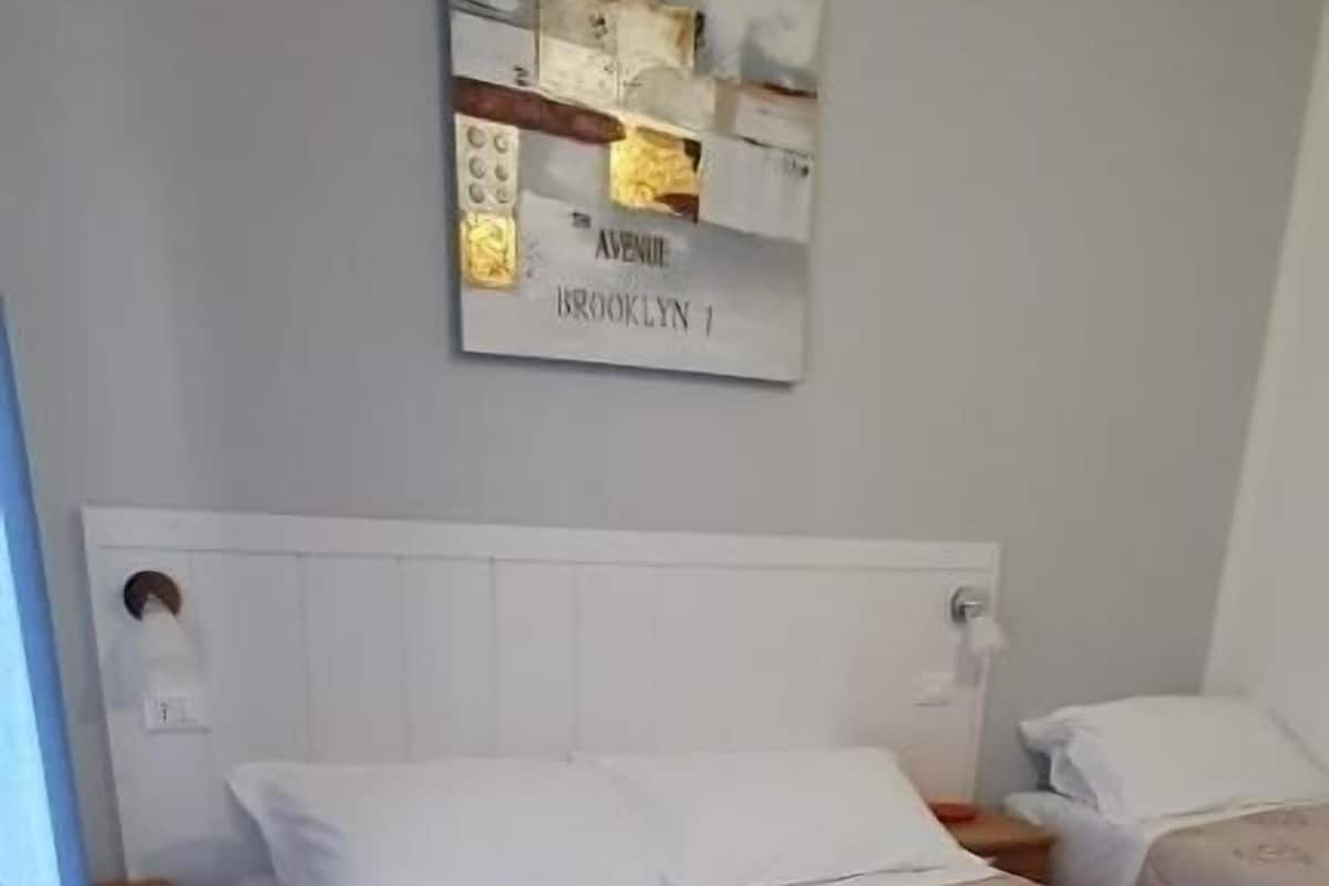 Ein Hotelzimmer mit einem Bett, einem Kopfteil, einer Wandleuchte und einem gerahmten Schild über dem Bett.