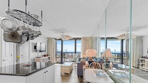 A modern hotel room with a kitchen, dining area, and balcony with a view. - Golden Sands 104 by Seaside Vacations & Sales (Ocean City)
