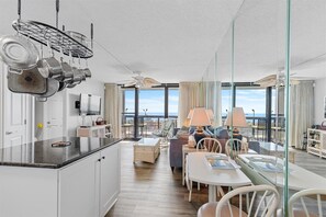 A modern hotel room with a kitchen, dining area, and balcony with a view. - Golden Sands 104 by Seaside Vacations & Sales (Ocean City)