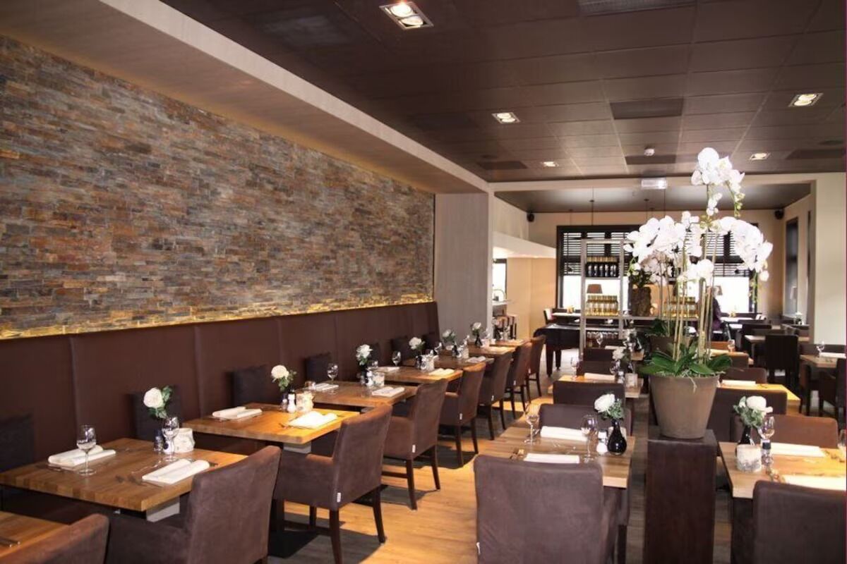 Ein Restaurant mit Holztischen und -stühlen, einer Ziegelwand und Topfpflanzen.