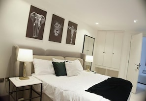 A hotel room with a bed, two bedside tables with lamps, a wardrobe, and three wall-mounted animal prints. - GE18 HOTELS  (Lagos)