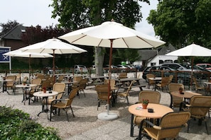 Outdoor seating with umbrellas, wicker chairs, and tables.