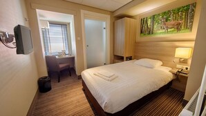Een hotelkamer met een bed, een bureau, een stoel, een schilderij en een lamp.