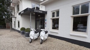 Un edificio con un cartello che riporta la scritta 'ENTREE' e due scooter parcheggiati davanti.