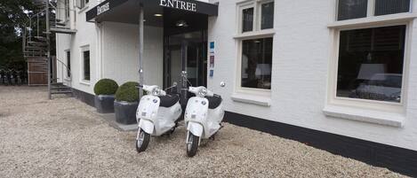 A building with a sign reading 'ENTREE' and two parked scooters in front.