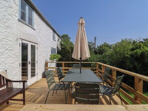 A deck with a table and chairs, a wooden bench, and a beige umbrella. - 2 Oak Tree Cottages (Axminster)