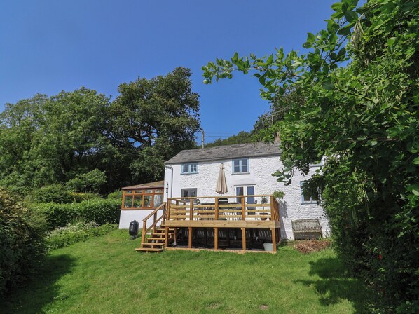 A white stone building with a wooden deck and a glass conservatory. - 2 Oak Tree Cottages (Axminster)