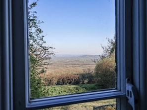 A window view of a landscape with a clear sky, distant fields, and some greenery. - 2 Oak Tree Cottages (Axminster)
