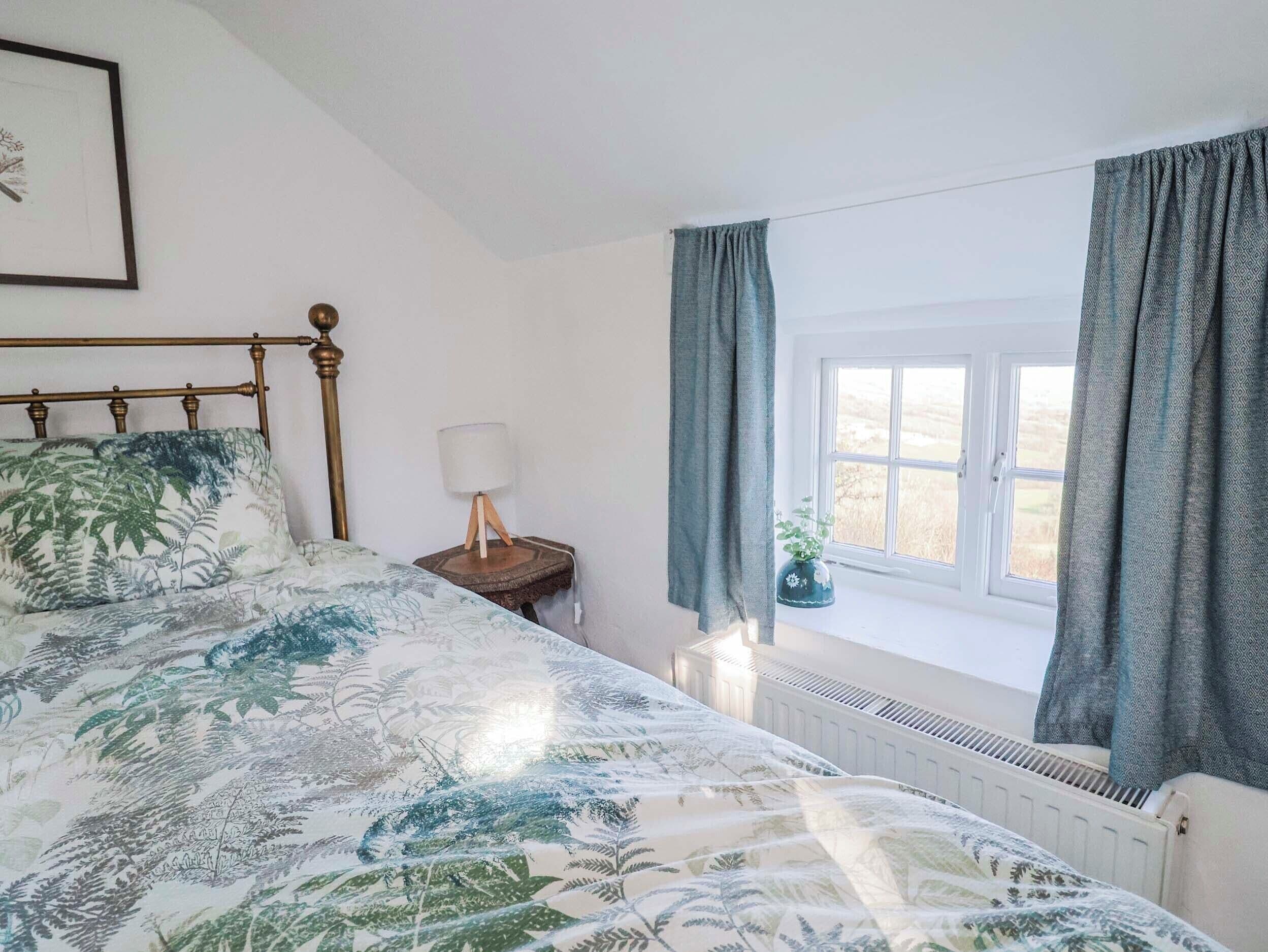 Une chambre à coucher avec un lit, une lampe de chevet, une fenêtre avec des rideaux et un radiateur.