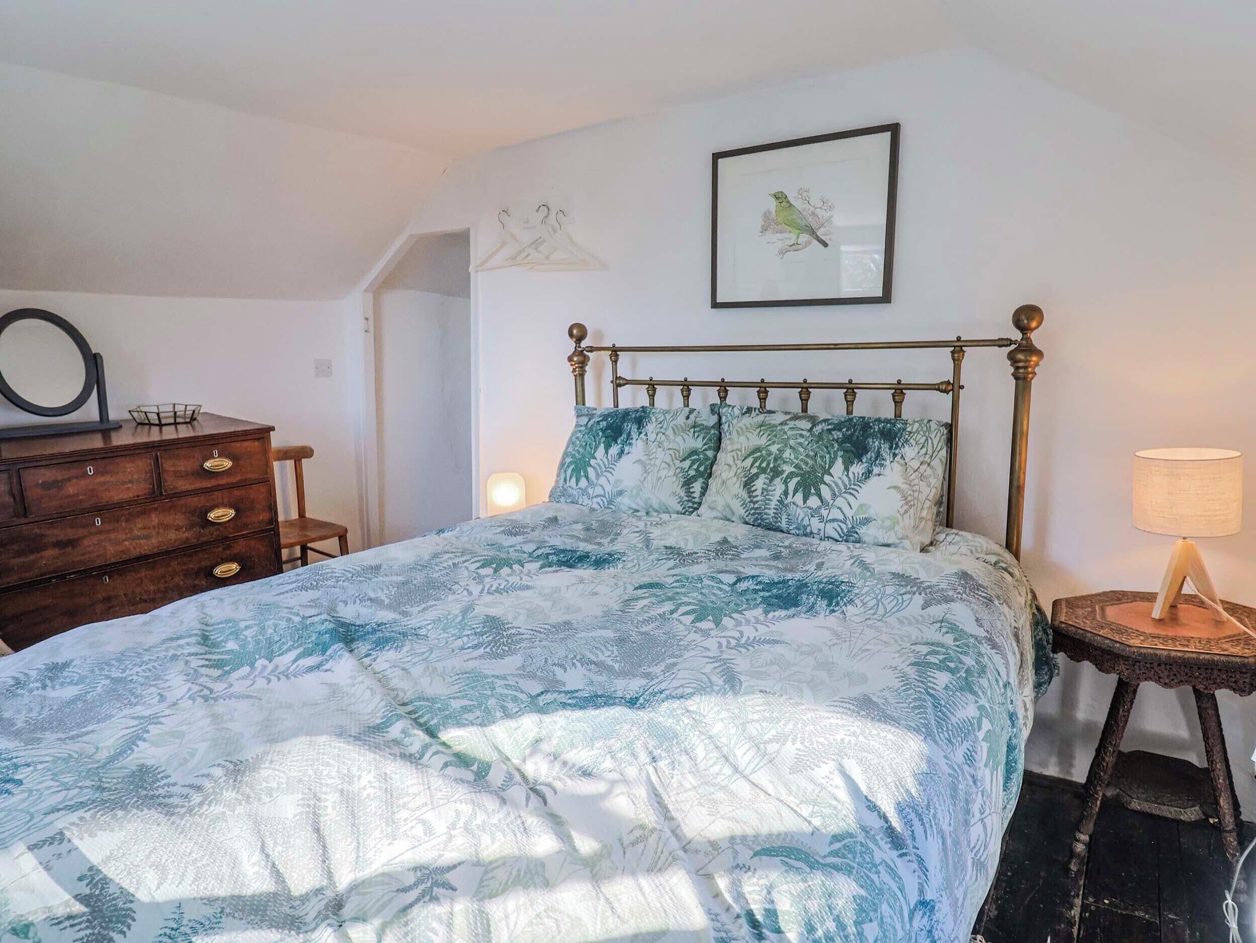 Un dormitorio con cama, cómoda, lámpara y un cuadro en la pared.