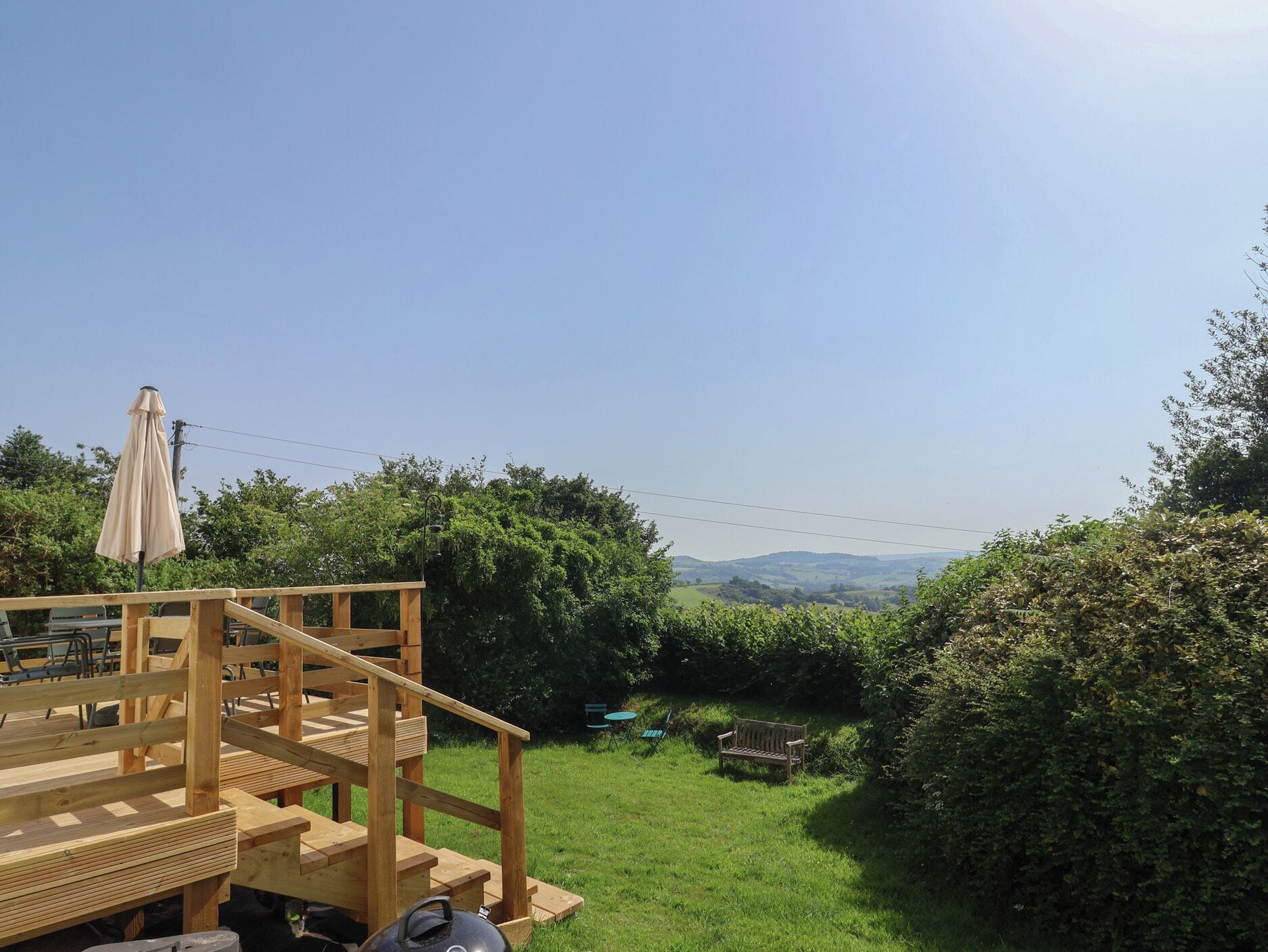 A wooden deck with a staircase, a table, and an umbrella.