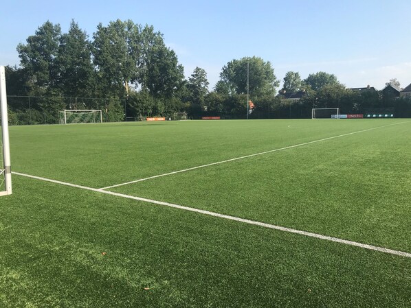 A soccer field with goalposts, a net, and a clear sky.