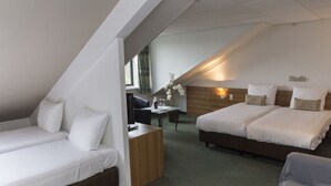 Hotellihuone, jossa on kaksi sänkyä, työpöytä ja tuoli.