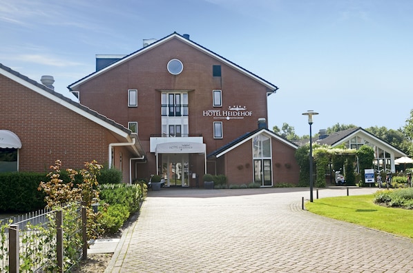 Un hotel con fachada de ladrillo, un cartel que dice 'HOTEL HEIDEHOF' y una entrada pavimentada.