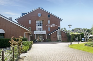 Ein Hotel mit Backsteinfassade, einem Schild mit der Aufschrift 'HOTEL HEIDEHOF' und einem gepflasterten Eingang.