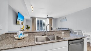 A modern kitchen with granite countertops, a stainless steel sink, and a built-in dishwasher. - 🌊Large Balcony-Gulf Views-Multiple Pools-Shores of Panama 925🌊 (Panama City Beach)
