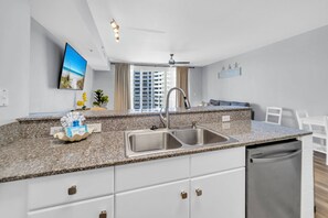 A modern kitchen with granite countertops, a stainless steel sink, and a built-in dishwasher. - 🌊Large Balcony-Gulf Views-Multiple Pools-Shores of Panama 925🌊 (Panama City Beach)