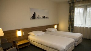 A hotel room with two beds, a desk with a lamp, a chair, a small table, and a painting on the wall. - Scenic Outdoor | Experience Scenic Adventure | Explore Famous Landmark (Heerenveen)