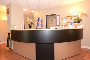 A reception desk with a black and beige color scheme, framed pictures on the wall, and a potted plant. - Scenic Outdoor | Experience Scenic Adventure | Explore Famous Landmark (Heerenveen)
