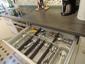 A kitchen with a drawer organizer for utensils, a coffee maker, and a kettle.