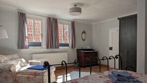 A bedroom with a bed, a sofa, a dresser, a radiator, and a window with curtains. - Historic wine farmhouse in Main/Wine Franconia at the foot of the Spessart (Triefenstein)