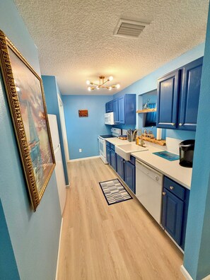 A kitchen with blue cabinets, a microwave, a coffee maker, and a wooden floor.