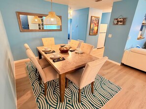 A dining area with a wooden table, chairs, and a patterned rug.