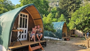 Ein Holz-A-Zelt mit einer Veranda, einer Sitzecke, einem kleinen Tisch und einem Stuhl.