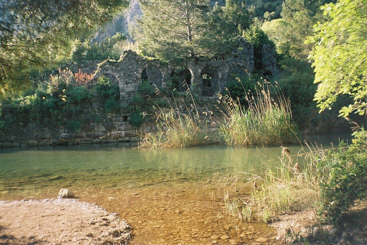 Un cadre naturel caractérisé par un plan d’eau aux eaux claires, des ruines de pierre et une végétation luxuriante.