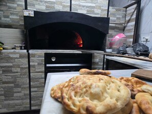Forn de pizza de rajola amb un mur de pedra de fons.