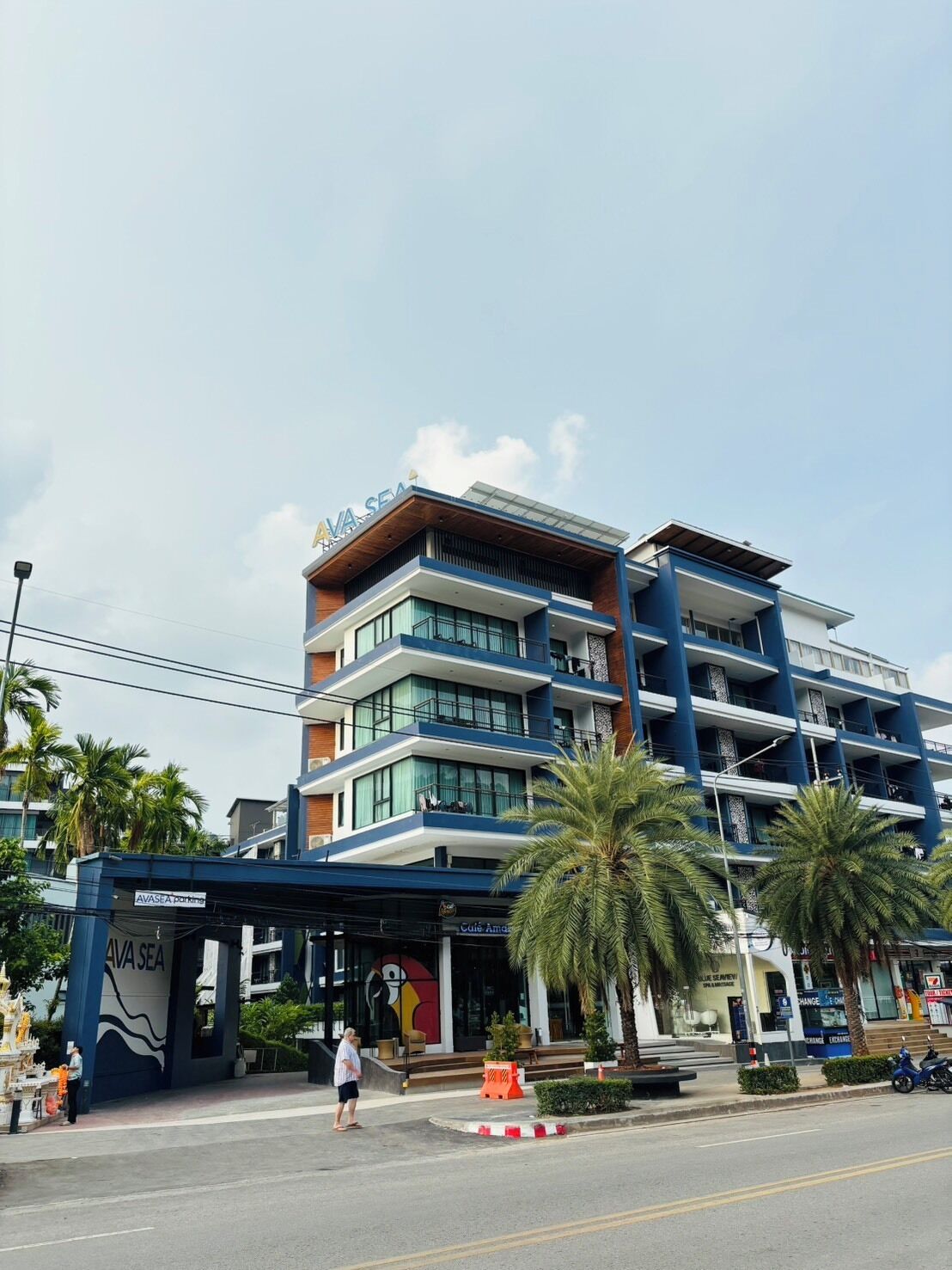 A multi-story hotel with a prominent 'AVA SEA' sign, a covered entrance, and palm trees in front.