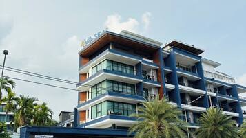 A multi-story hotel with a prominent 'AVA SEA' sign, a covered entrance, and palm trees in front.