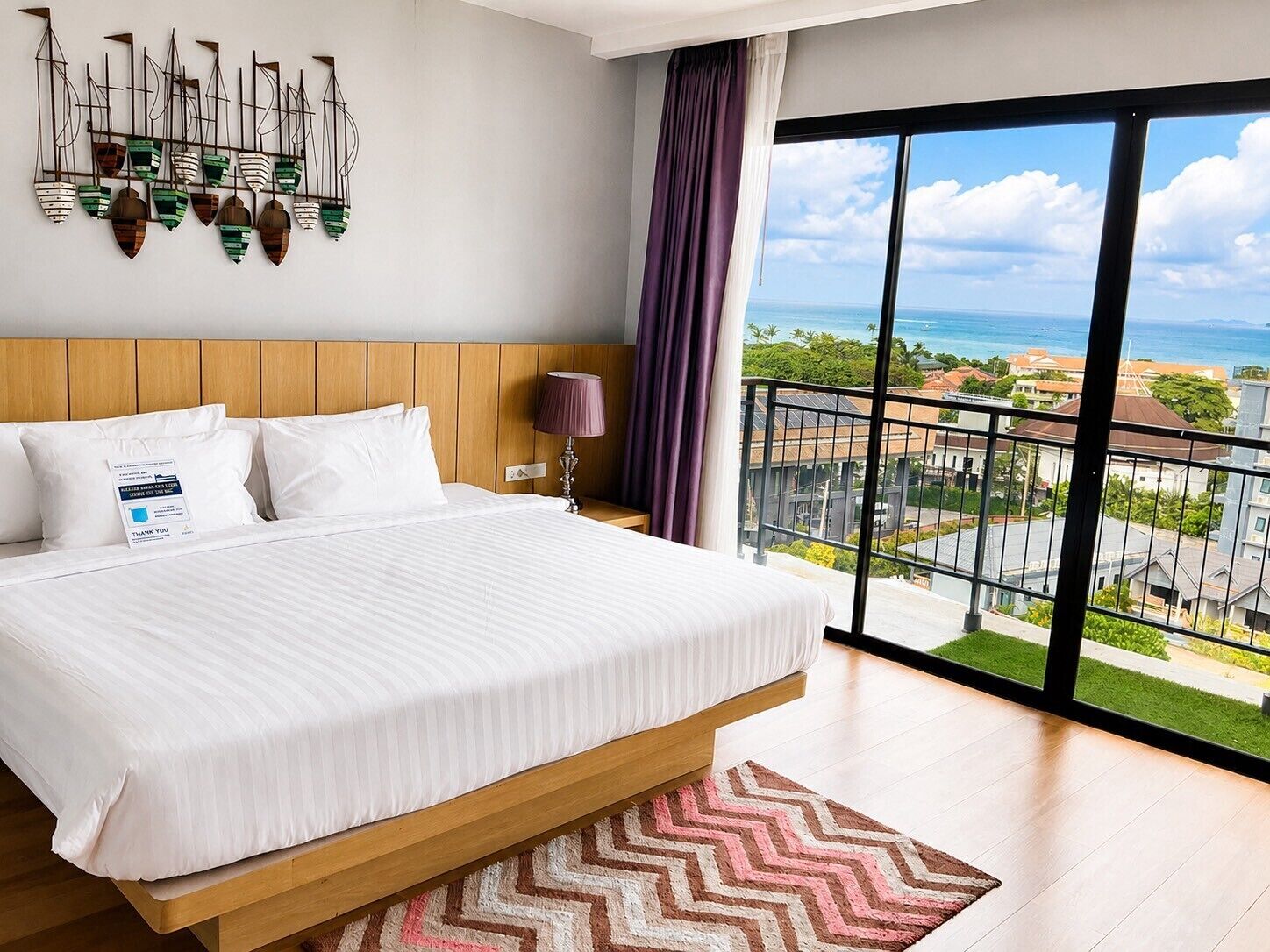 A hotel room with a large bed, a view of the sea, and a balcony.