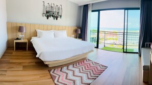 Ein modernes Hotelzimmer mit einem großen Bett, Meerblick, einem Balkon und einer Wanddekoration.